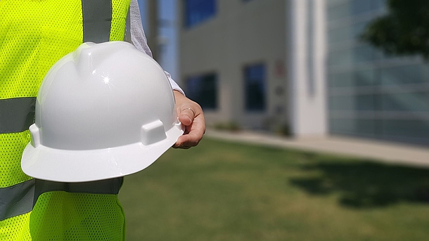 Darstellung einer Person in Warnweste mit Helm